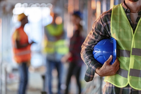 A worker in a hard hat clutches his shoulder, superimposed on text about work injuries and workers' compensation.